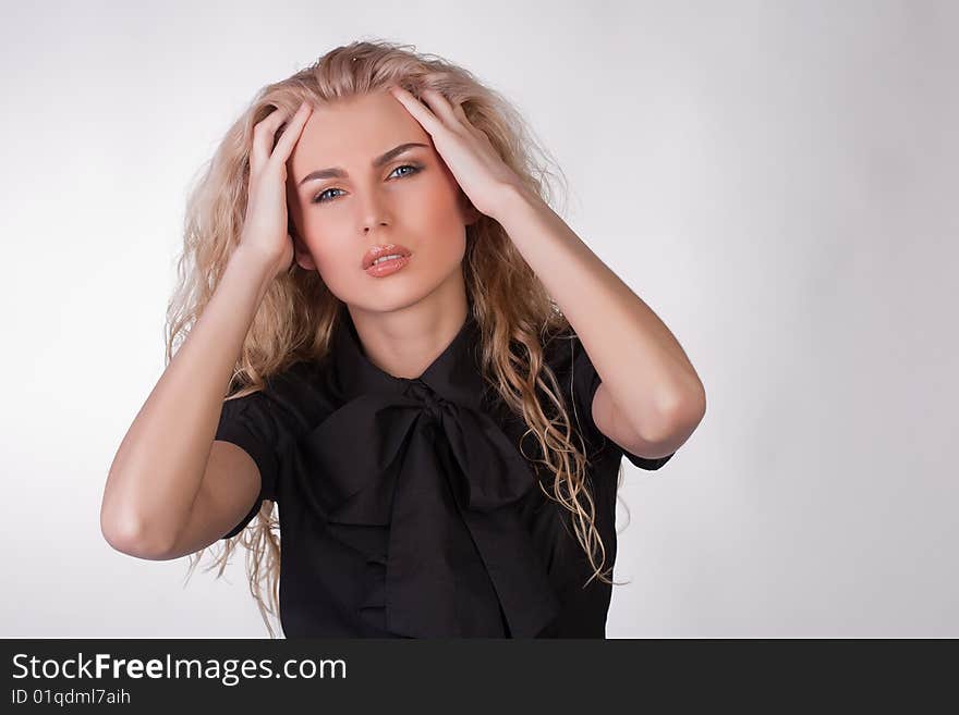 Blond young woman with a pounding headache, studio shot