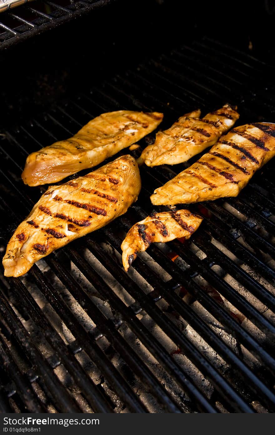 Five pieces of chicken cooking on the barbeque. Five pieces of chicken cooking on the barbeque