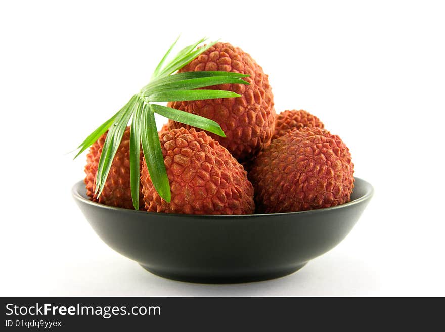 Group of lychee and green leaf in a black dish with clipping and a white background. Group of lychee and green leaf in a black dish with clipping and a white background