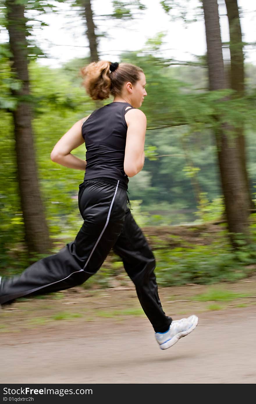 Sportive young woman running over a forrest road