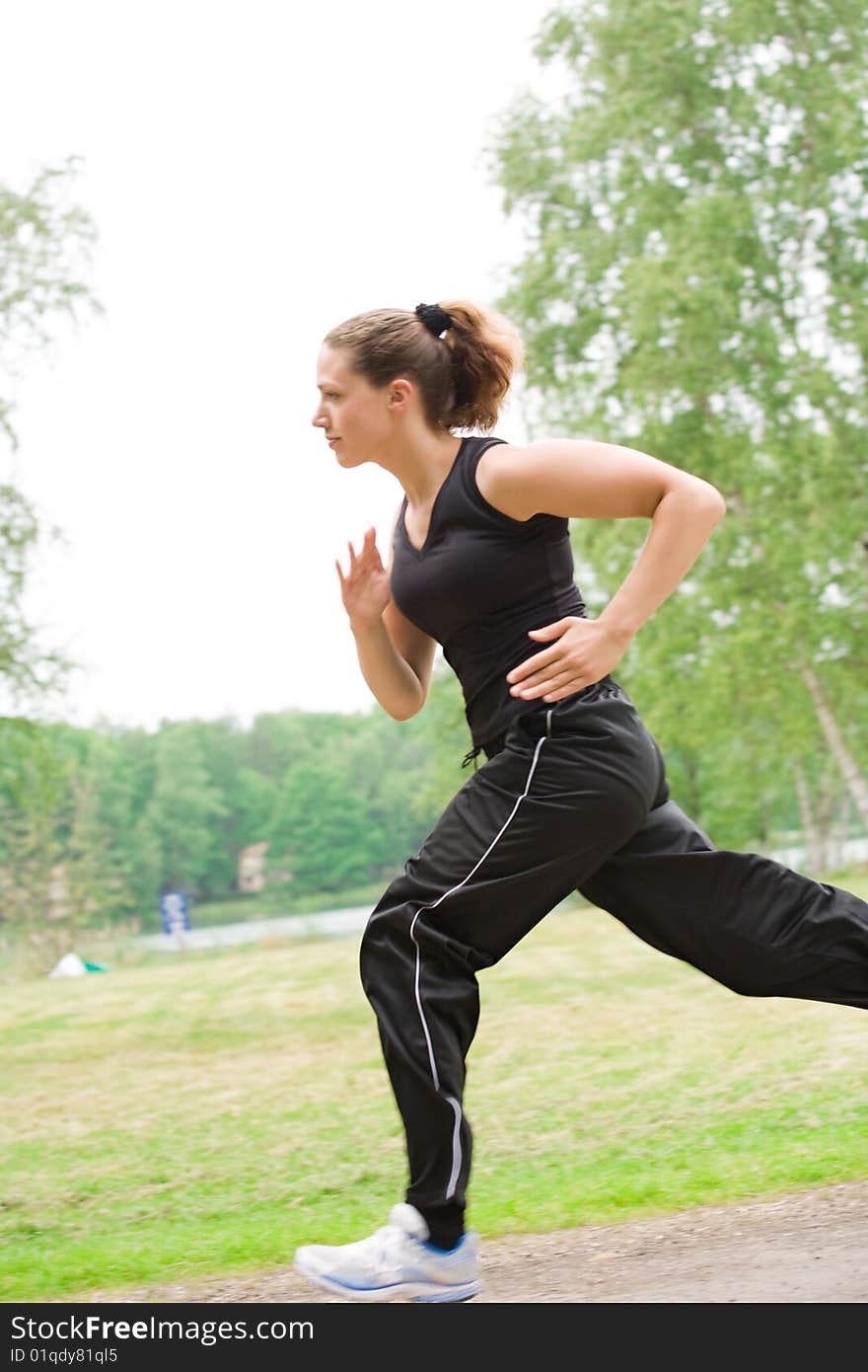 Sportive young woman running over a forrest road