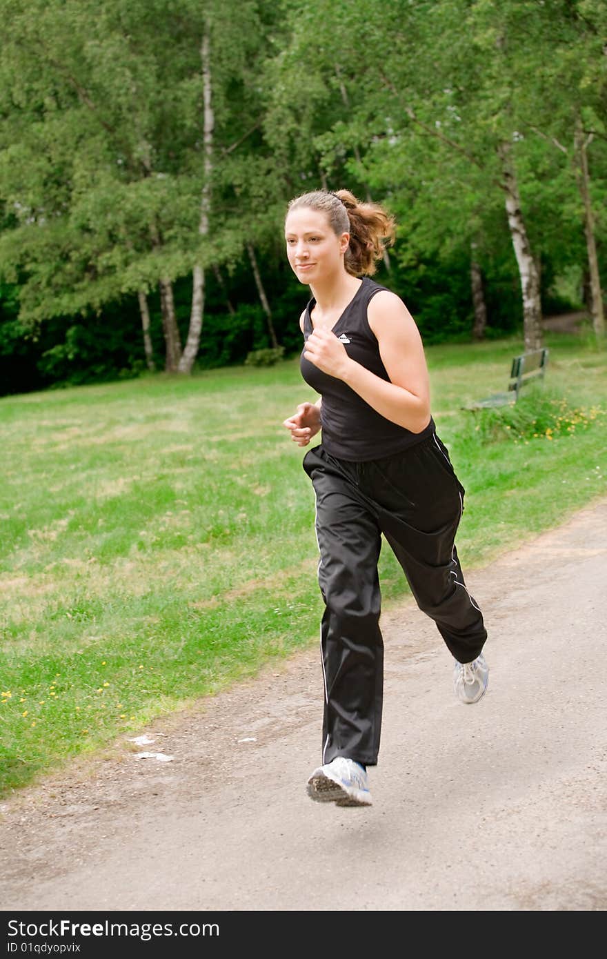 Sportive young woman running over a forrest road