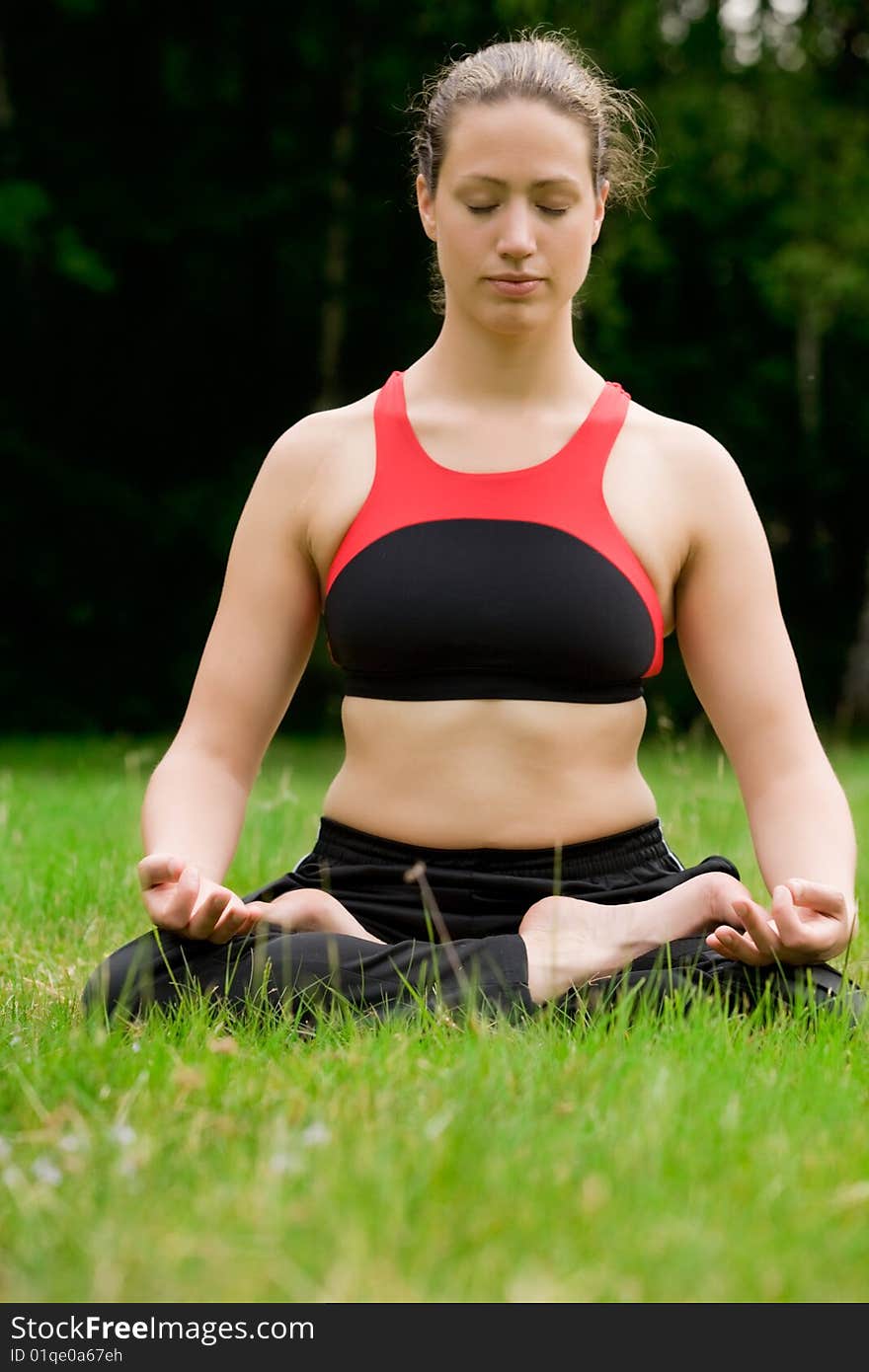 Practising yoga in a green field with trees