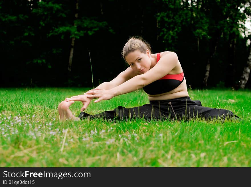 Practising Yoga In A Green Field With Trees