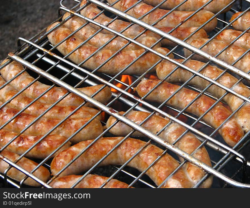 Sausages on the grill with fire on the background