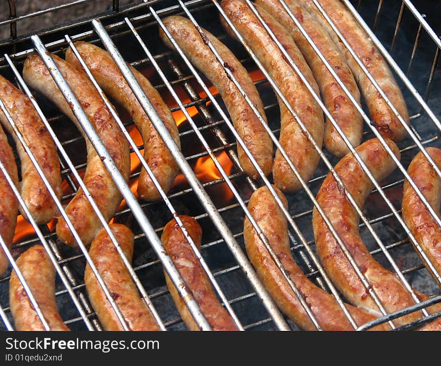 Sausages on the grill with fire on the background