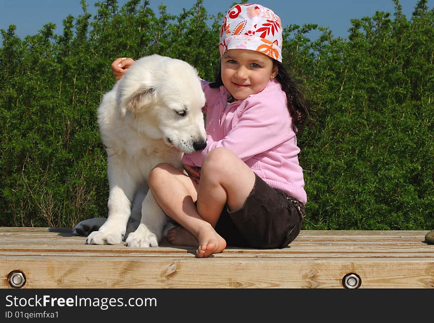 Little girl with a Golden retriever puppy sitting near the beach