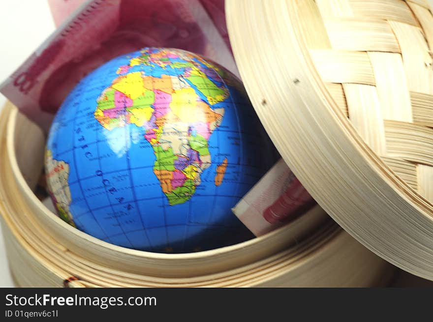 A globe and some chinese currency in a dim sum basket. A globe and some chinese currency in a dim sum basket