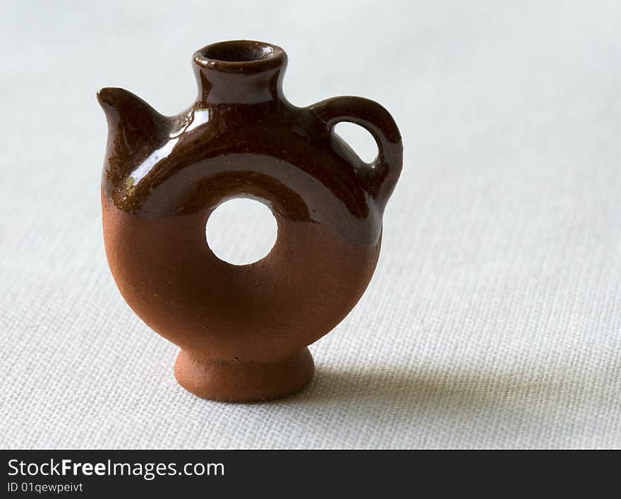 Orange clay ceramic kettle, shaped rounder at the bottom, and more narrow at the top with a handle.  Isolated on white background.