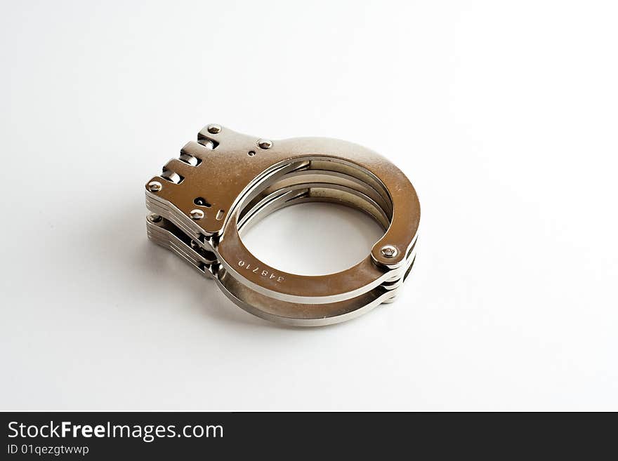 A pair of hinged handcuffs isolated on a white background.