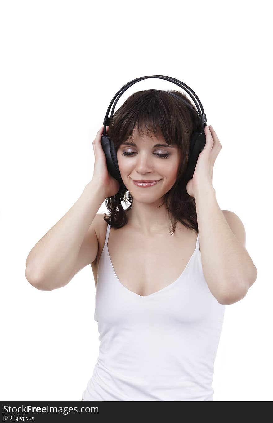 The beautiful girl in a white vest listens to music and smiles, having closed eyes from pleasure. The beautiful girl in a white vest listens to music and smiles, having closed eyes from pleasure