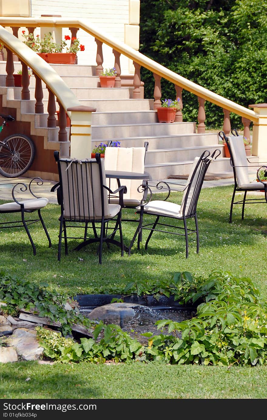 House stairs  with flowerpots and tables on lawn in yard. House stairs  with flowerpots and tables on lawn in yard