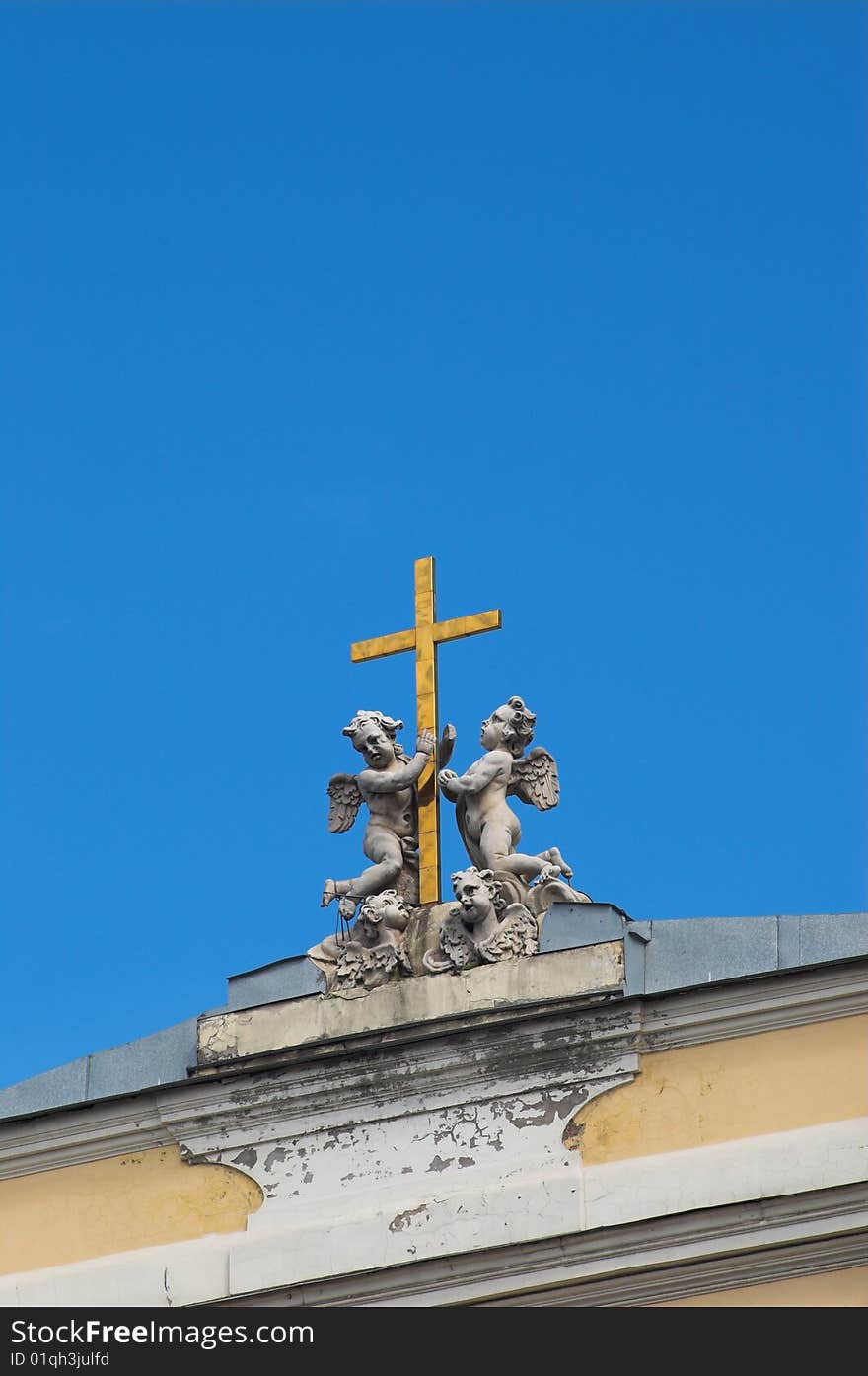 Sculptures of angels are holding a gold cross on the roman catholic church of St. Ekaterina in St.Petersburg