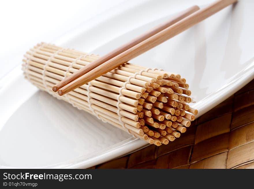 A pair of chopsticks and a sushi mat