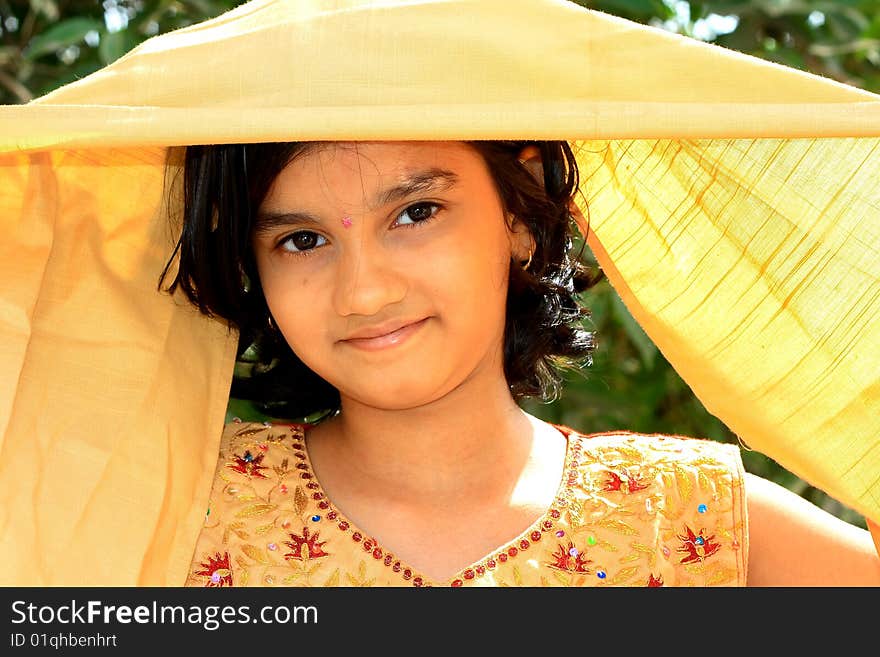 A traditional Indian girl lifting her golden veil to reveal her bright and beautiful face. A traditional Indian girl lifting her golden veil to reveal her bright and beautiful face.