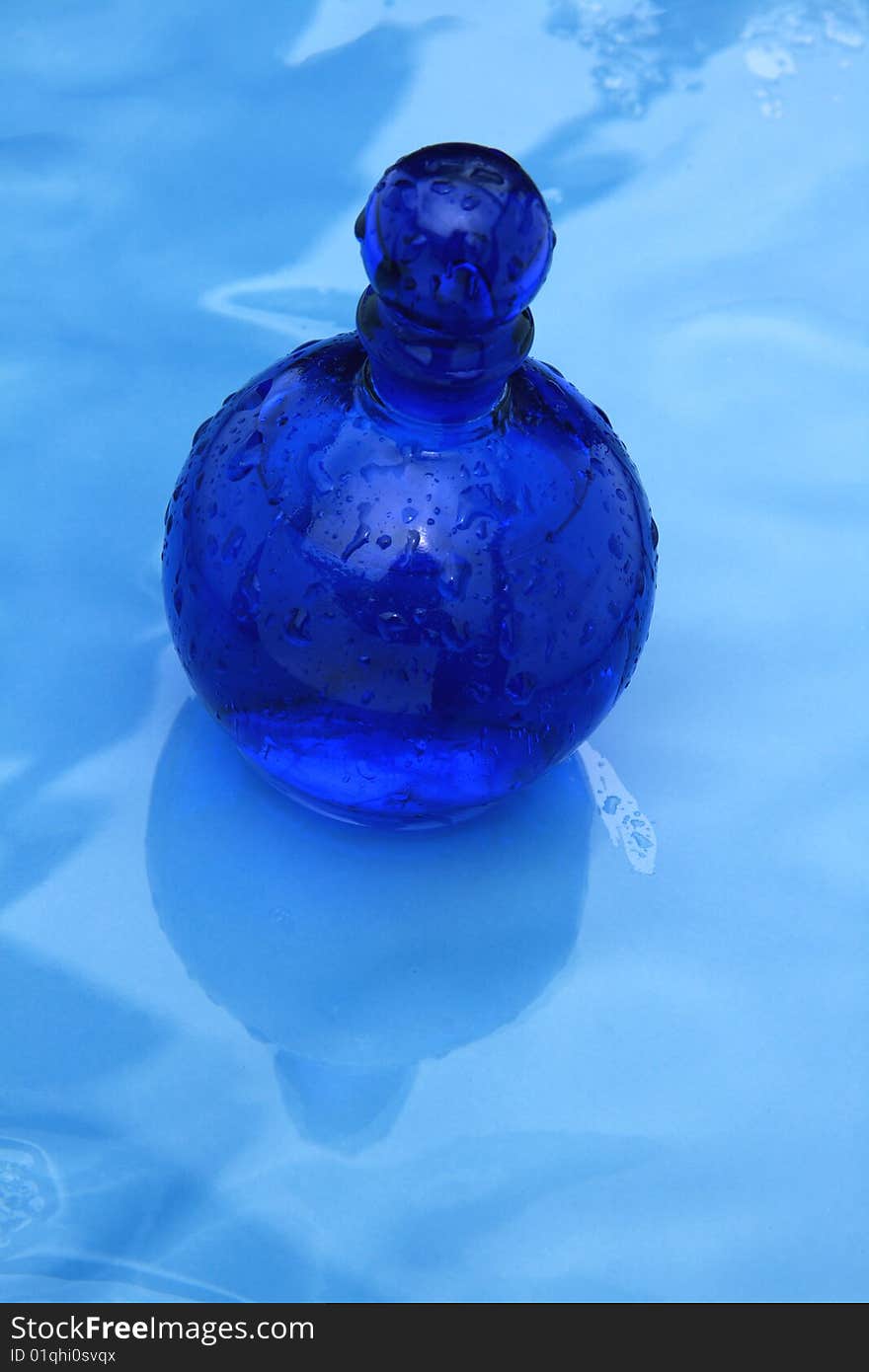 Blue small bottle on a wet glazing background. Blue small bottle on a wet glazing background