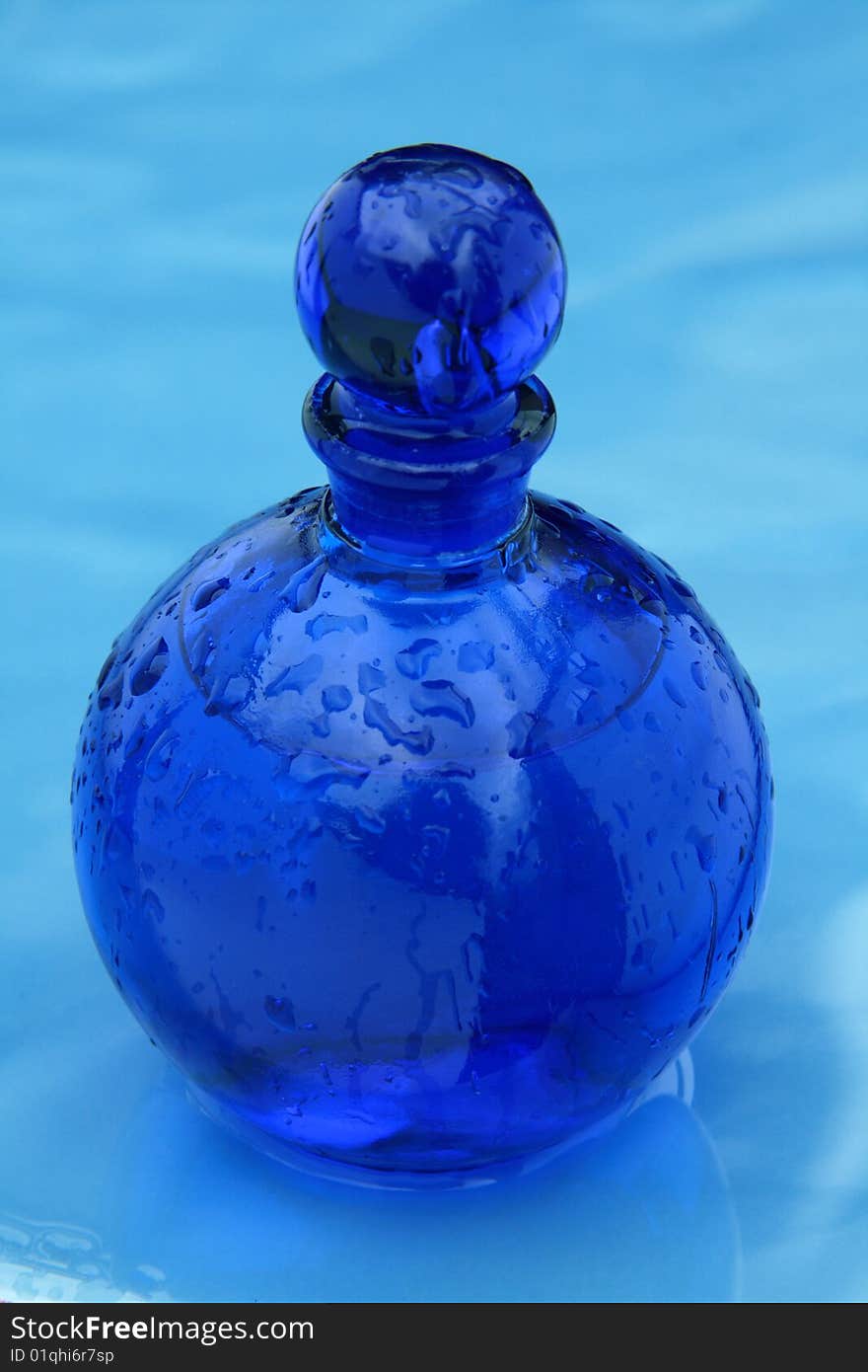 Blue small bottle on a wet glazing background. Blue small bottle on a wet glazing background