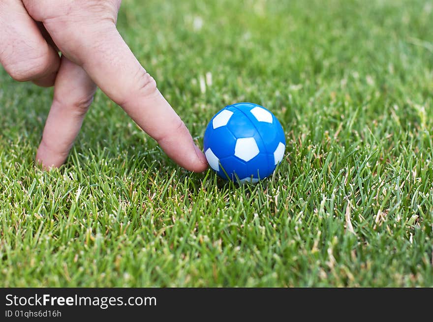 Man hand plaiyng role of soccer player with small blue ball. Man hand plaiyng role of soccer player with small blue ball