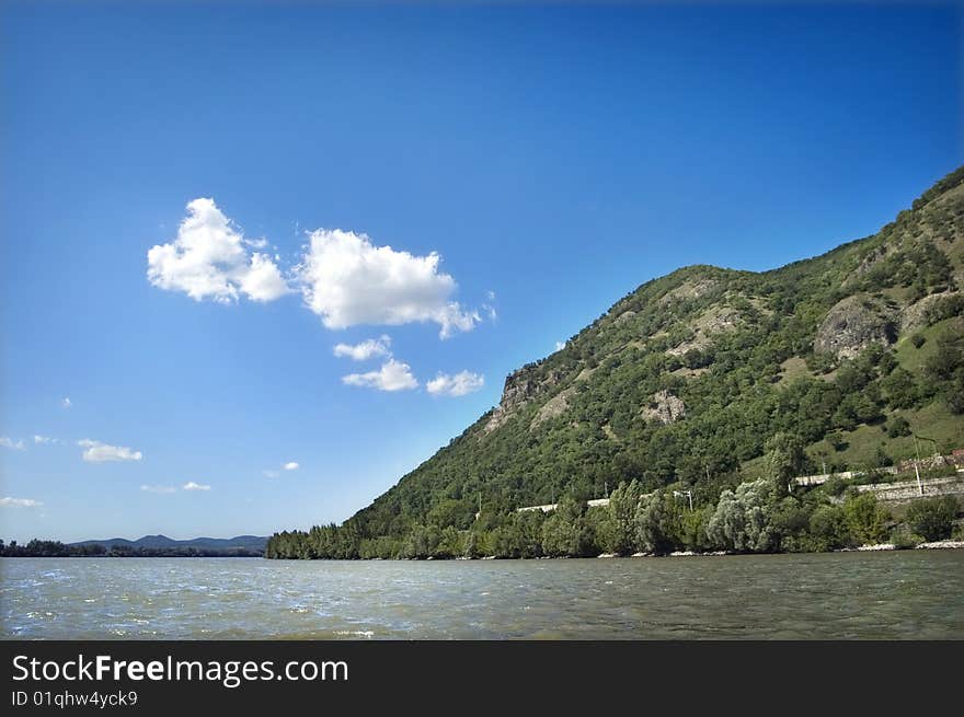 Landscape with river and green hills and clouds at the background