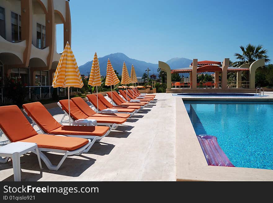 Sunbeds and umbrellas near resort's pool. Sunbeds and umbrellas near resort's pool