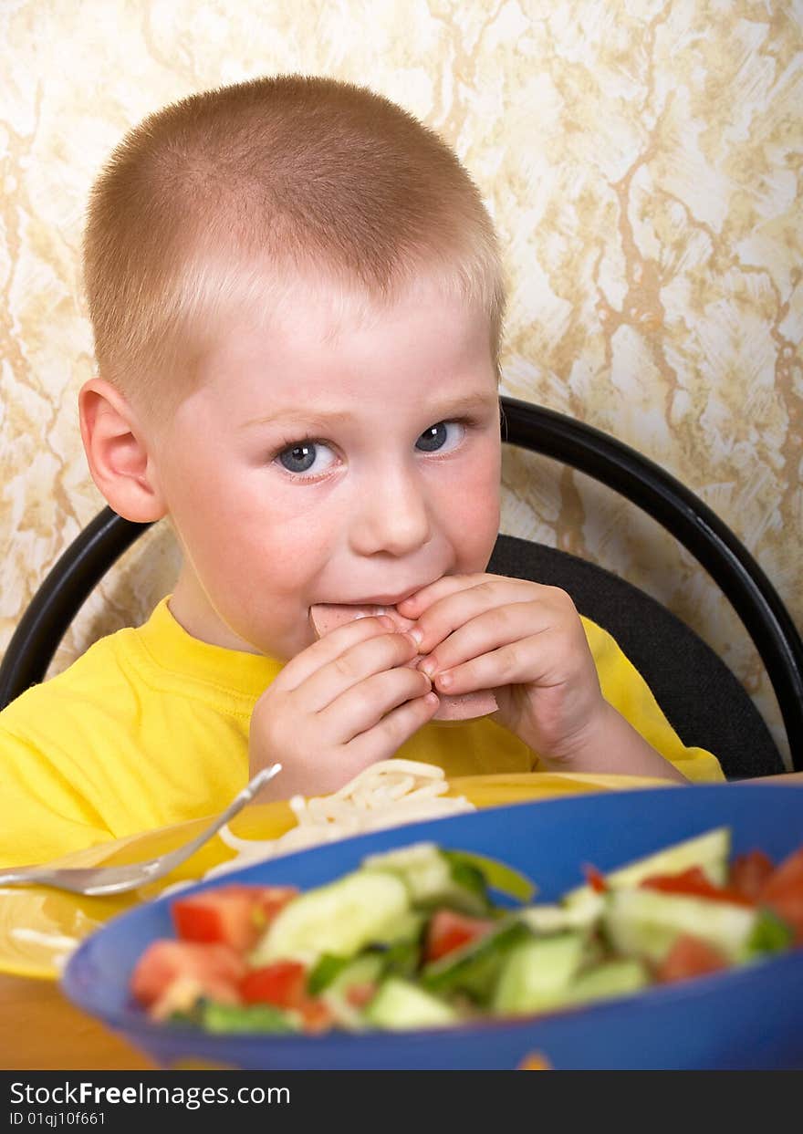 The little boy eats fresh salad. The little boy eats fresh salad