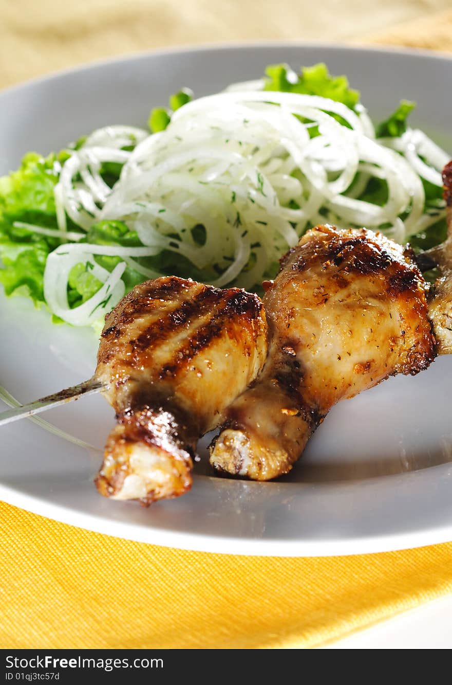 Grilled Chicken Legs on Skewer with Pickled Onions and Salad Leaf