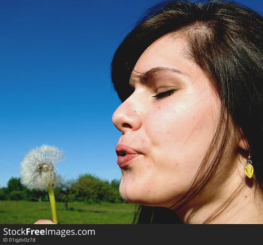 Young woman blowing on flower