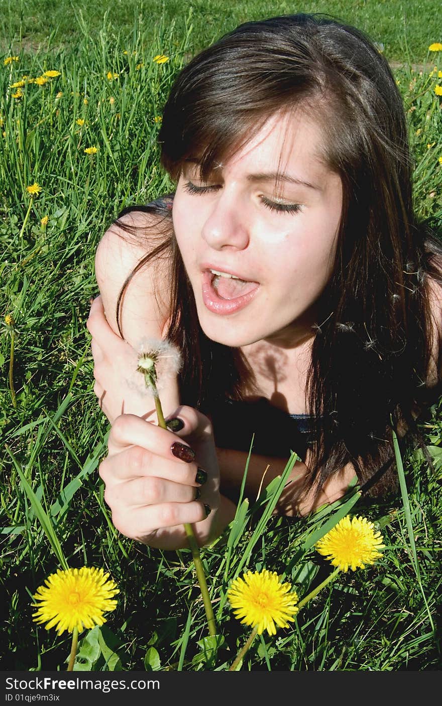 Young woman blowing on flower