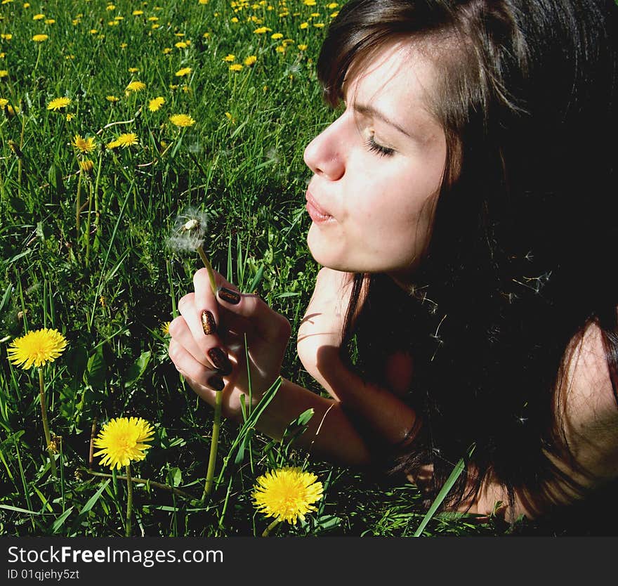 Young woman blowing on flower