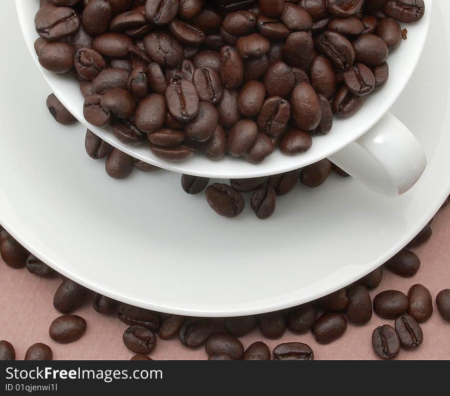 Cup and saucer filled with coffee beans.