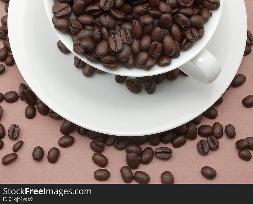 Cup and saucer filled with coffee beans.