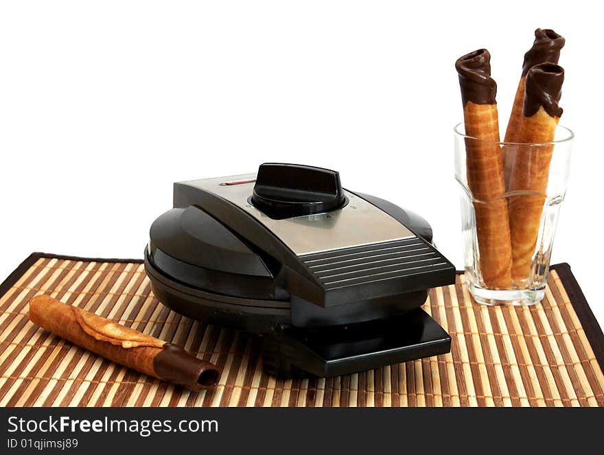 Wafer- roll with chocolate in a glass and waffle iron on a background. Wafer- roll with chocolate in a glass and waffle iron on a background