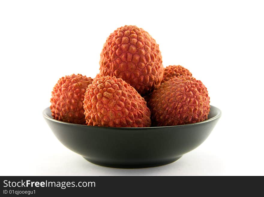 Group of lychee in a black dish with clipping and a white background