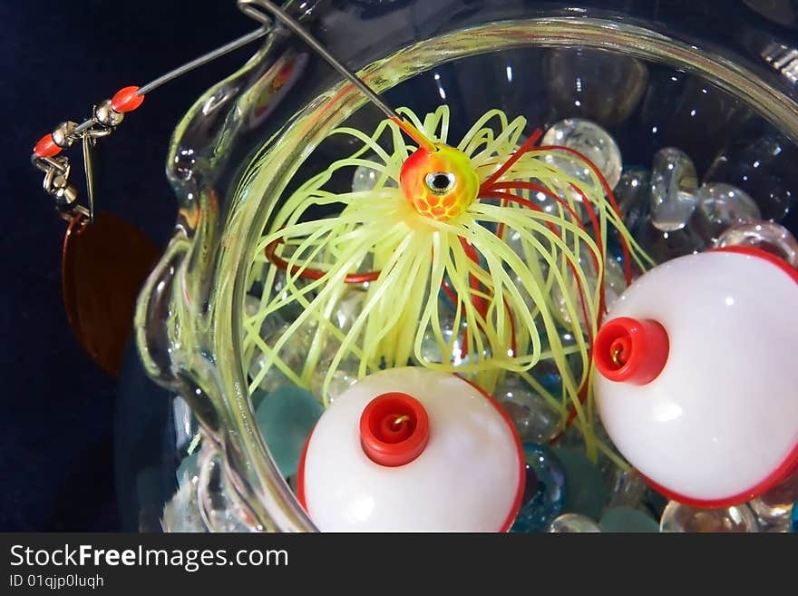 Bobber and fishing lure in a glass bowl of pebbles. Bobber and fishing lure in a glass bowl of pebbles.