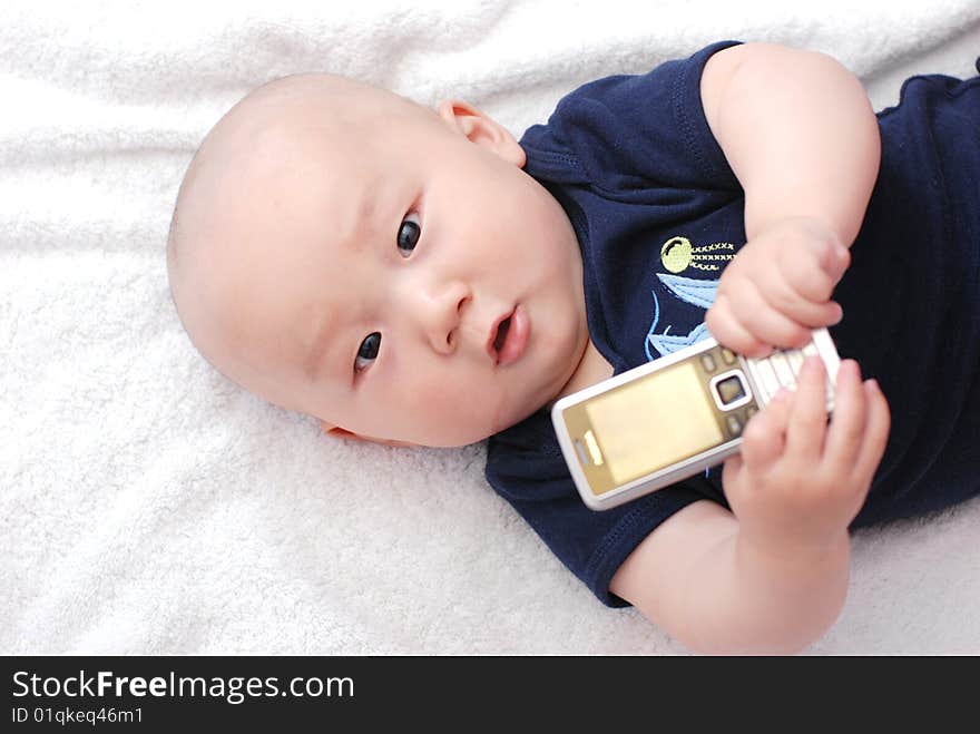 Cute little baby boy holding a cellphone on bed. Cute little baby boy holding a cellphone on bed