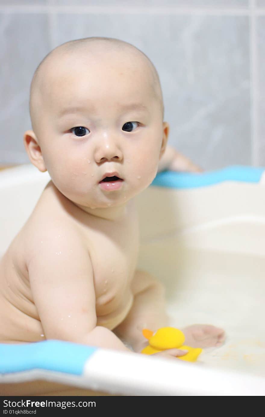 Asian baby boy holding  a yellow plastic duck in bath. Asian baby boy holding  a yellow plastic duck in bath