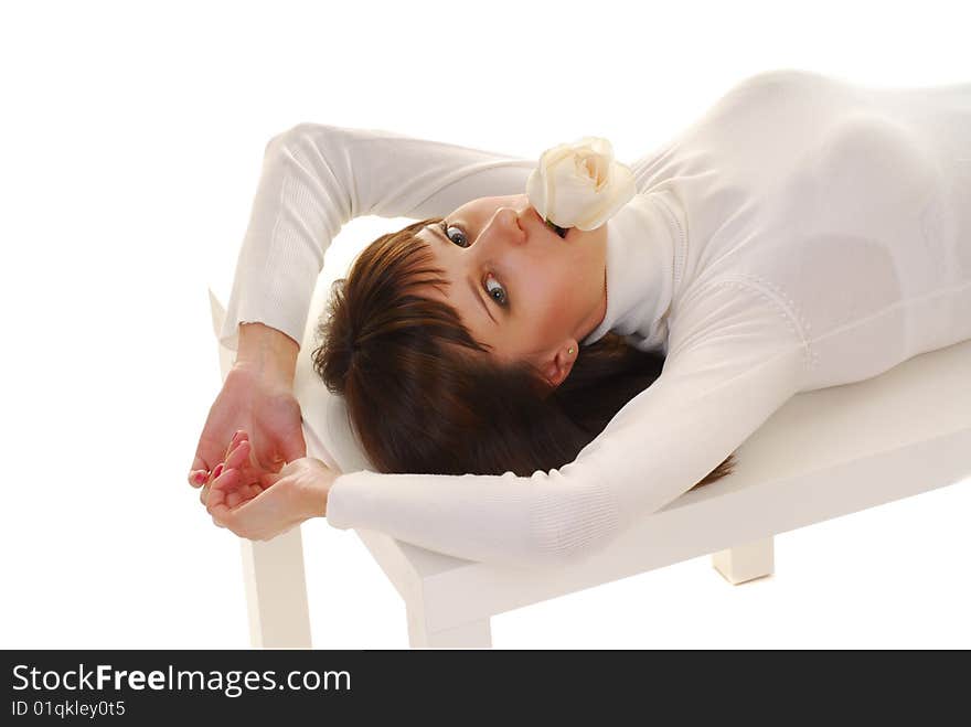 Young woman in white dress whith white roses in yer hands laying on table isolated on white. Young woman in white dress whith white roses in yer hands laying on table isolated on white