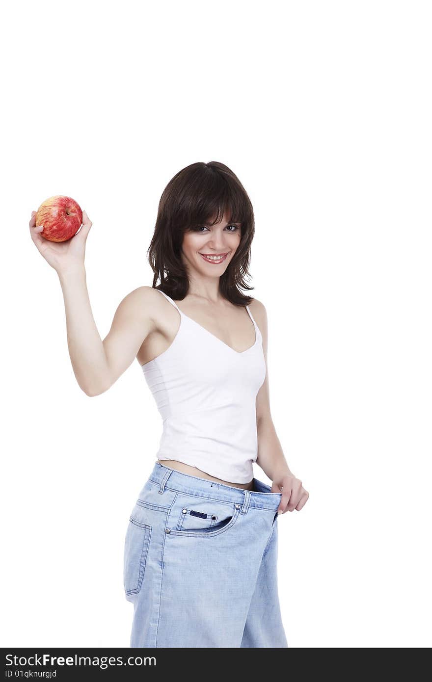 The beautiful girl in jeans of the big size holds a red apple in a hand. The beautiful girl in jeans of the big size holds a red apple in a hand