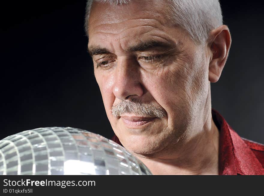 Old man looking at discoball isolated on black