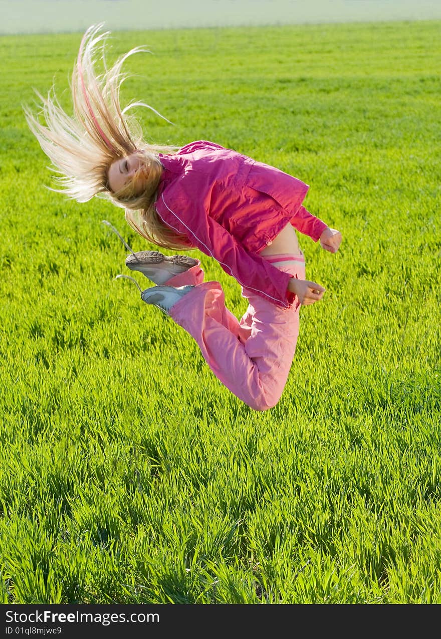 Beautiful young woman jumps above green meadow. Beautiful young woman jumps above green meadow