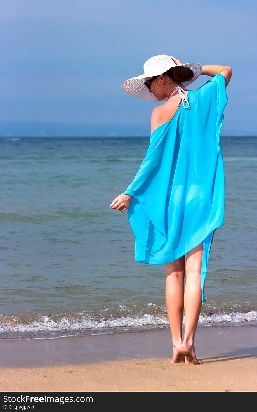 Brunette girl with white hat standing on the beach