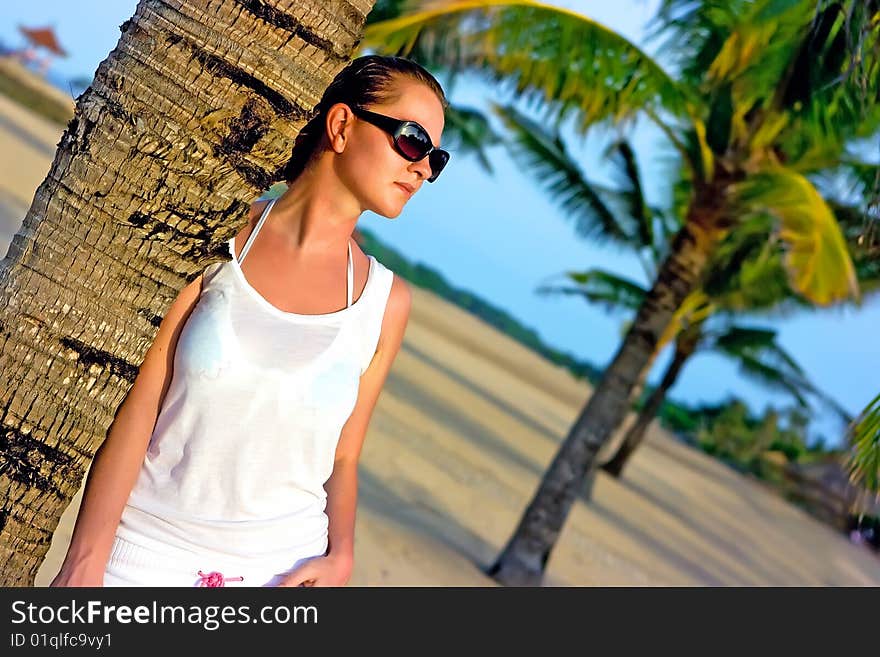 Beautiful brunette in sunglasses standing leaning on palm. Beautiful brunette in sunglasses standing leaning on palm