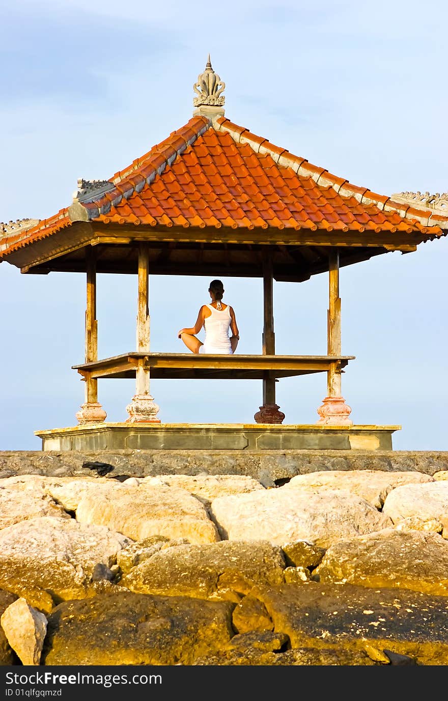 Brunette girl sitting in lotos pose and meditating in pagoda. Brunette girl sitting in lotos pose and meditating in pagoda