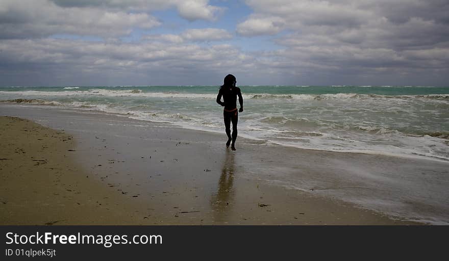 Man running on the beach near the blue sea over cloudy sky. Man running on the beach near the blue sea over cloudy sky