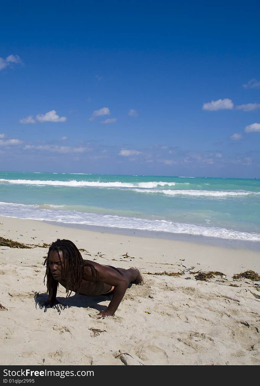 Black man making pumps ont the beach over blue sea and blue sky. Black man making pumps ont the beach over blue sea and blue sky