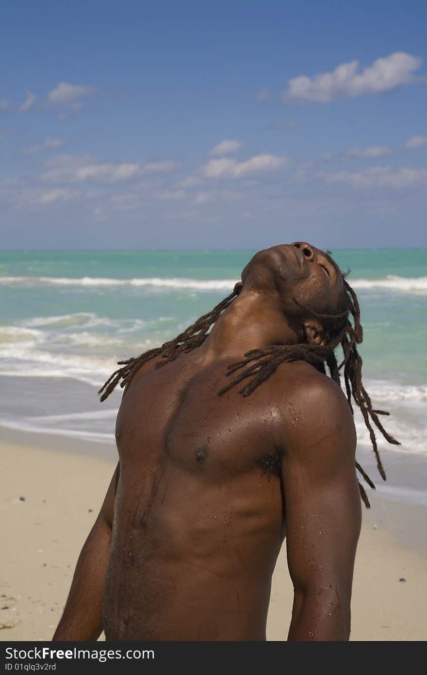 Black man tilting his head behind on the beach over blue sea and blue sky. Black man tilting his head behind on the beach over blue sea and blue sky