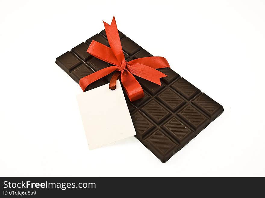 Black chocolate with red ribbon and card isolated on white