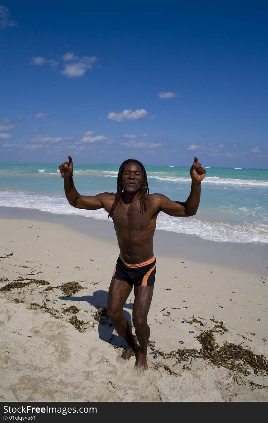 Black man dancing on the beach back in the blue sea over blue sky. Black man dancing on the beach back in the blue sea over blue sky