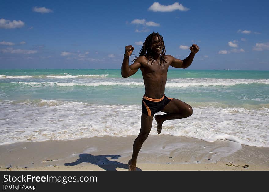 Black man jumping on the beach over blue sea and blue sky. Black man jumping on the beach over blue sea and blue sky