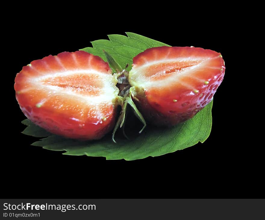 Close up halves of strawberry laying on a green leaf